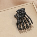 Close-up of gothic glossy black skeleton hand hair claw clip on a golden textured tray - Single Piece / Black