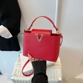 Elegante bolso de mano tejido rojo con detalle V dorado y correa sobre un fondo de moda - Rojo
