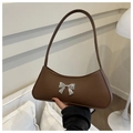 Detail of a dark brown leather baguette bag featuring a silver metal bow and slim handle - Brown