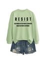 Flachbild eines hellgrünen Sweatshirts mit RESIST-Print und zerrissenen Jeansshorts - S / Olivgrün (Schwarze Schrift)