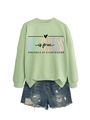 Détail du sweat vert clair Kindness is Free assorti à un short en jean déchiré - Sweat-shirt vert olive (motif de texte noir)