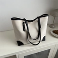 Bolso tote de lona minimalista con ribete de cuero negro en un acogedor ambiente hogareño - Blanco
