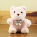 Pink plush bear charm with grey silk bow and pearl accents on wooden background - Pink