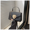 Détail d'un sac enveloppe noir avec fermoir coeur doré et bandoulière en chaîne - Noir