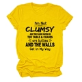 Close-up of yellow cotton T-shirt with I'M NOT CLUMSY JUST black graphic text print - S / Tops / Yellow