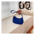 Blue quilted mini shoulder bag with gold chain and white pompom detail in lifestyle setting - Blue