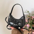 Glossy black crescent dumpling bag with bow detail and silver beads held by model - Black