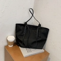 Large black nylon tote bag with long shoulder straps shown in an urban lifestyle setting - Black