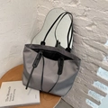 Minimalist grey nylon tote bag with black leather handles shown on a wooden table - Gray