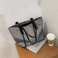 Detailed macro view of the dark grey tote bag fabric texture with black slim shoulder straps - Gray