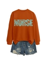 Detailed view of orange nurse crewneck sweatshirt paired with distressed denim shorts - Burnt Orange