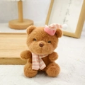 Brown plush bear keychain wearing pink striped knit hat and scarf on white lace - Dark Brown