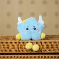 Close-up of a blue plush cloud charm with white wings and yellow pompoms on a basket - Blue