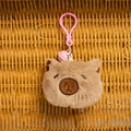 Close-up of cute plush capybara keychain with pink bell and carabiner on woven background - Dark Brown