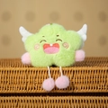 Close-up of green star plush charm with embroidered smile and white wings on a basket - Green