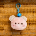 Pink plush bear head charm with blue bell and checkered ears on a woven background - Pink