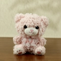 Pink plush teddy bear with lace bib and embroidered paws on a wooden surface - Pink Bear