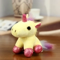 Mini yellow plush unicorn keychain with pink sequins and rainbow hair on wooden background - Sitting Yellow