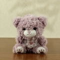Cute mauve plush teddy bear with lace scarf and pink paw prints on a wooden table - Purple Bear