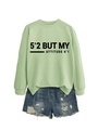 Détail du sweat-shirt vert clair avec slogan et short en jean déchiré au style vintage - Vert Olive (Police Noire)