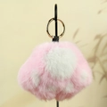 Pendentif patte de chat en peluche rose et blanc avec boucle dorée sur fond beige - Rose