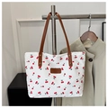 Detail der weißen Shopper-Tasche mit Kirschmuster und braunen Ledergriffen - Weiß