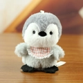 Cute grey and white penguin plush keychain with pink lace bib on wooden background - F Penguin