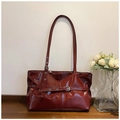 Dettaglio borsa in pelle lucida bordeaux con fibbie metalliche e cinturini decorativi - Rosso