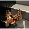 Detail der Leoparden-Hobo-Tasche mit Metallkette und Bärenanhänger auf Luxusbuch - Braun mit Anhänger