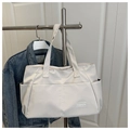 Primer plano de un bolso tote de lona crema con parche de cuero y bolsillo lateral - Blanco Roto