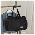 Detalle del bolso tote de nailon negro con bolsillos laterales y etiqueta de moda - Negro