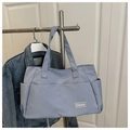 Detalle del bolso tote de nailon azul claro con tejido resistente y logo de moda - Azul grisáceo
