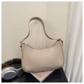 Detail of beige crescent underarm bag with embossed fashion text on minimal props - Khaki