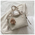 Detail of beige tote bag with a small brown teddy bear charm on white bedding - With Charm / Khaki