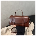 Detail of vintage caramel leather handbag featuring decorative straps and round buckle - Dark Brown