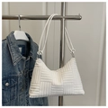 Detail of white tote bag with textured quilting on a display rack with denim jacket - White