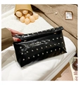 Macro detail of glossy black faux leather shoulder bag with decorative silver rivets - Black