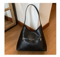 Detail of black woven texture shoulder bag with shiny gold metal buckle on wood floor - Black