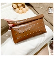 Close-up of a dark brown clutch bag with silver rivets held against a wool coat - Brown