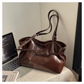 Detailaufnahme der tiefbraunen glänzenden Ledertasche mit verstellbarem Riemen und Dekor - Braun
