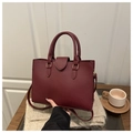 Detail of burgundy leather tote bag with lychee texture and sturdy top handles - Red