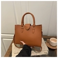Detailed close-up of brown pebbled leather tote bag with gold magnetic clasp and strap - Brown