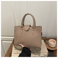 Close-up of taupe genuine leather tote bag with lychee texture and gold hardware - Khaki