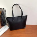 Detalle de bolso tote minimalista de cuero sintético negro con costuras en mesa de madera - Negro