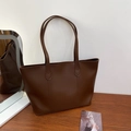 Detalle de un bolso tote de cuero PU marrón con costuras decorativas en V sobre madera - Marrón