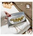 Detail der silbernen Lederhandtasche mit goldfarbenem Wellendesign und feiner Metallkette - Silber