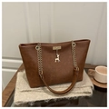Deep brown PU leather tote bag with gold chain strap and deer pendant in a warm setting - Brown