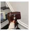 Detail van donkerbruine suède crossbodytas met zilveren robotbedel en rits - Bruin