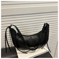 Detail of black crescent shoulder bag with golden logo plaque and long tassels on white book - Black