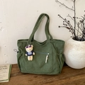 Bolso tote de pana verde oscuro con colgante de oso en un ambiente acogedor interior - Verde con Colgante